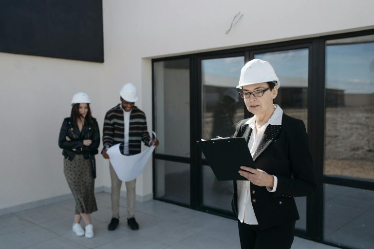 Architects in hard hats examining construction plans at a building site.