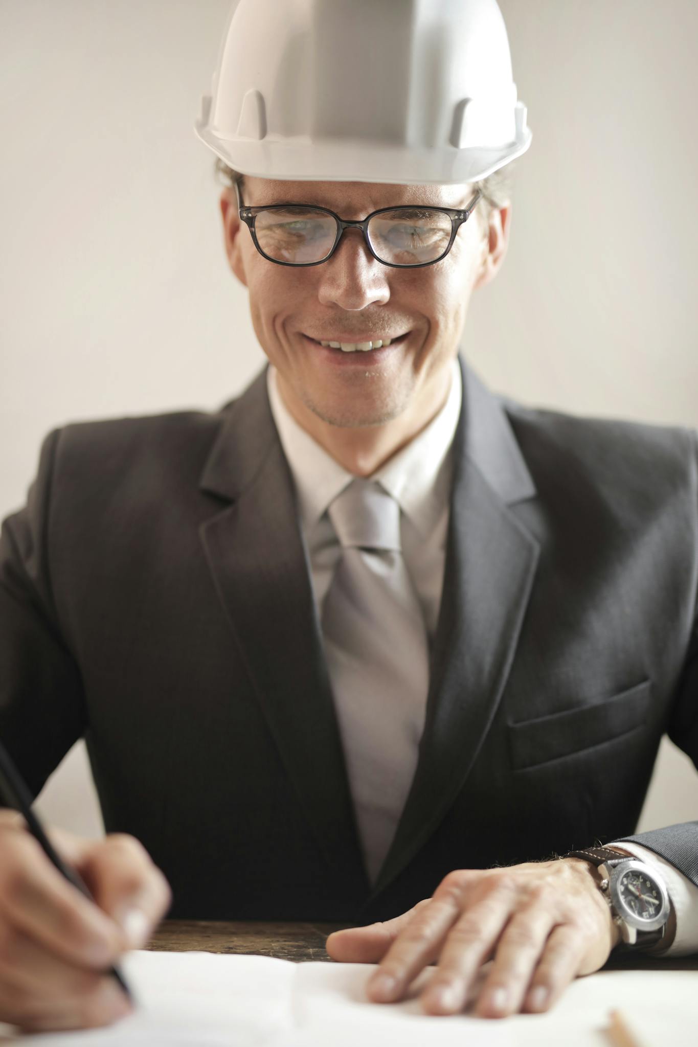 Male engineer in formal attire reviewing and signing construction documents indoors.